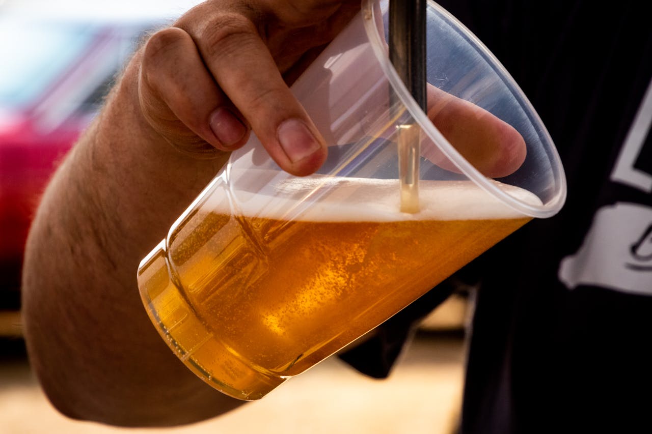 journey Close-up of a person pouring golden craft beer into a clear plastic cup.